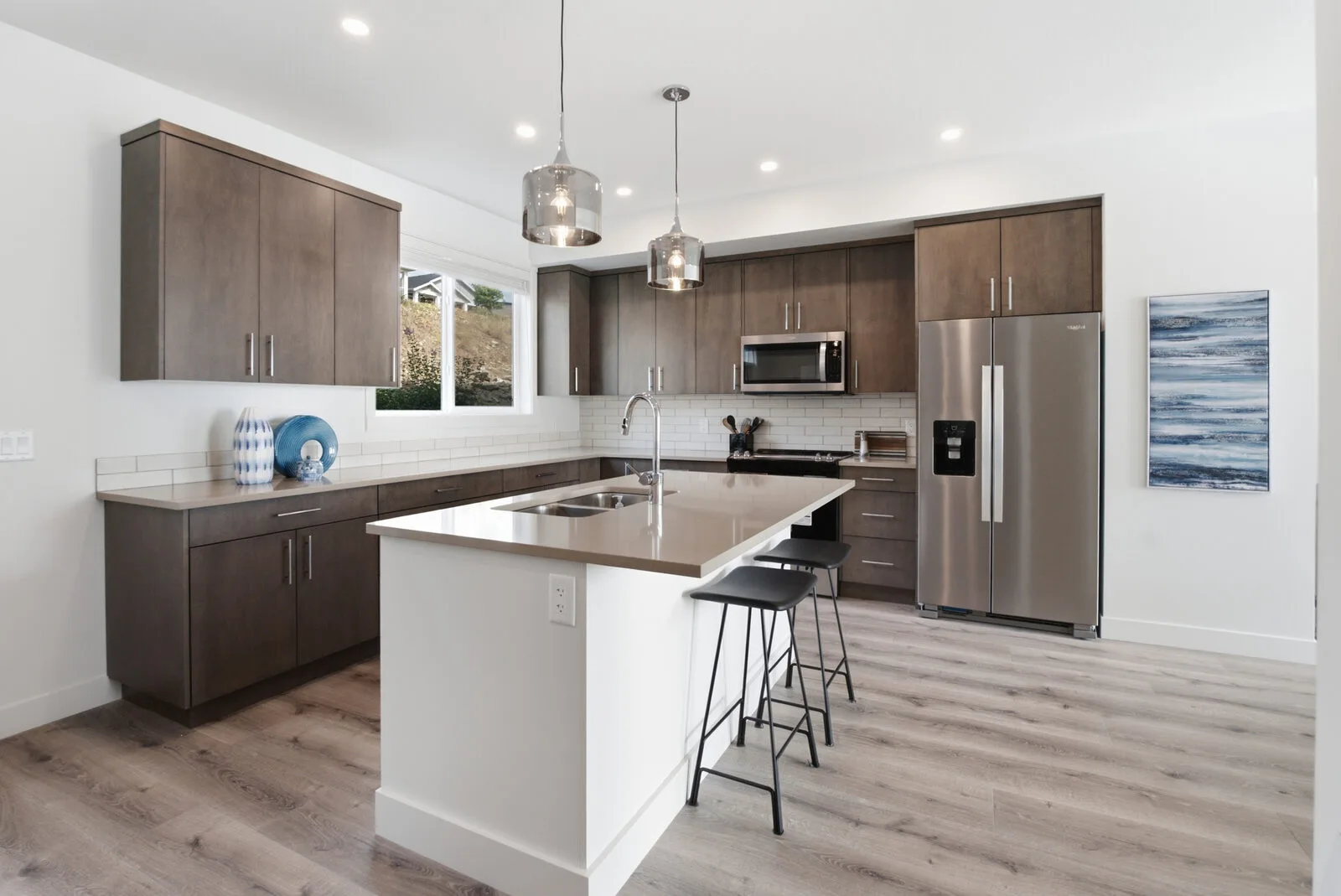 Kitchen with open-concept island, pendant lighting and stainless steel appliances at Academy Ridge