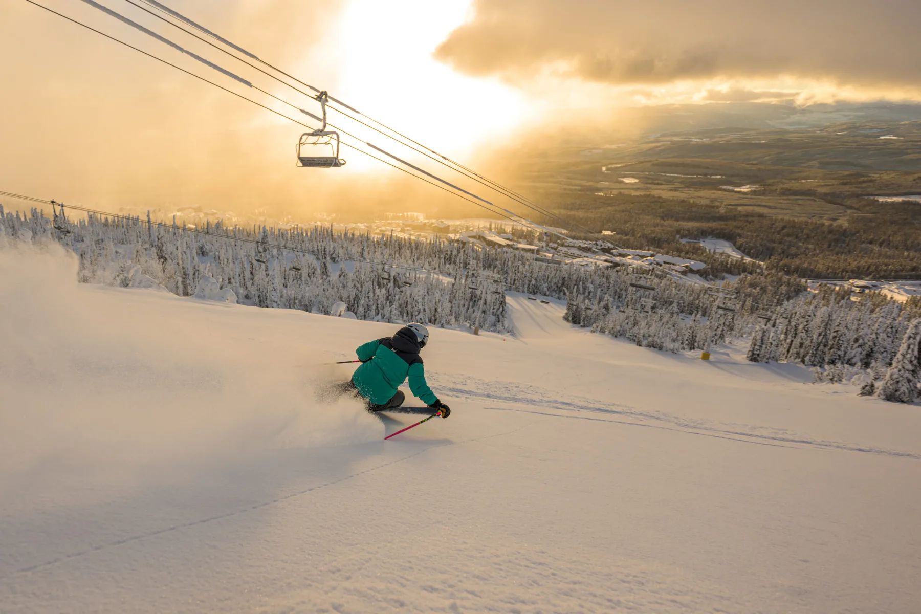 A skier carving fresh powder at sunrise above the Okanagan Valley
